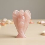 Rose Quartz Angel Figurine held in hand with cream background and soft flower petals