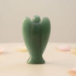 Green Aventurine Angel Figurine held in hand with cream background and soft flower petals