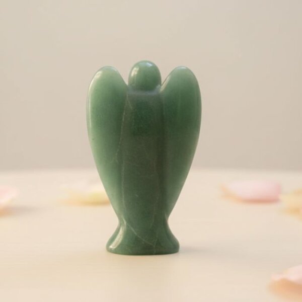 Green Aventurine Angel Figurine held in hand with cream background and soft flower petals