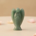 Green Aventurine Angel Figurine held in hand with cream background and soft flower petals