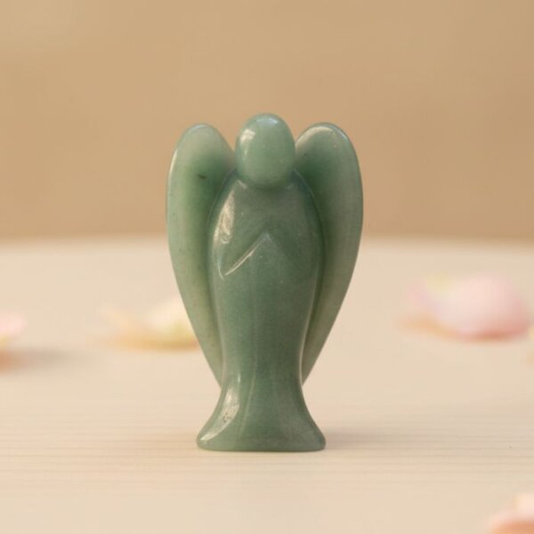 Green Aventurine Angel Figurine held in hand with cream background and soft flower petals