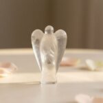 Clear Quartz Angel Figurine held in hand with cream background and soft flower petals