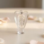 Clear Quartz Angel Figurine held in hand with cream background and soft flower petals