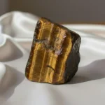 Tiger Eye Raw Stone featuring a natural unpolished crystal with golden-brown bands and a rich earthy texture.